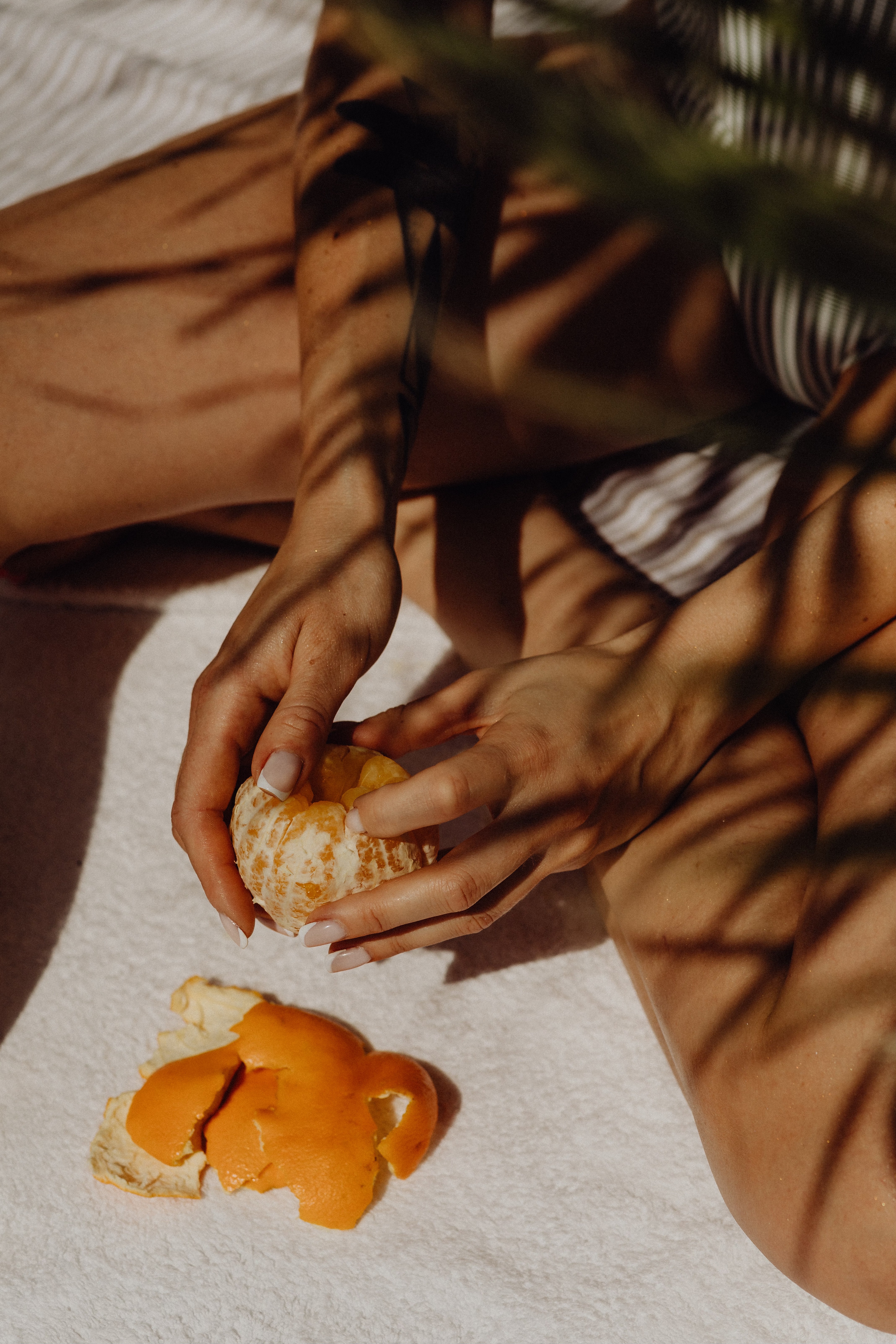woman peeling orange, with light shadows